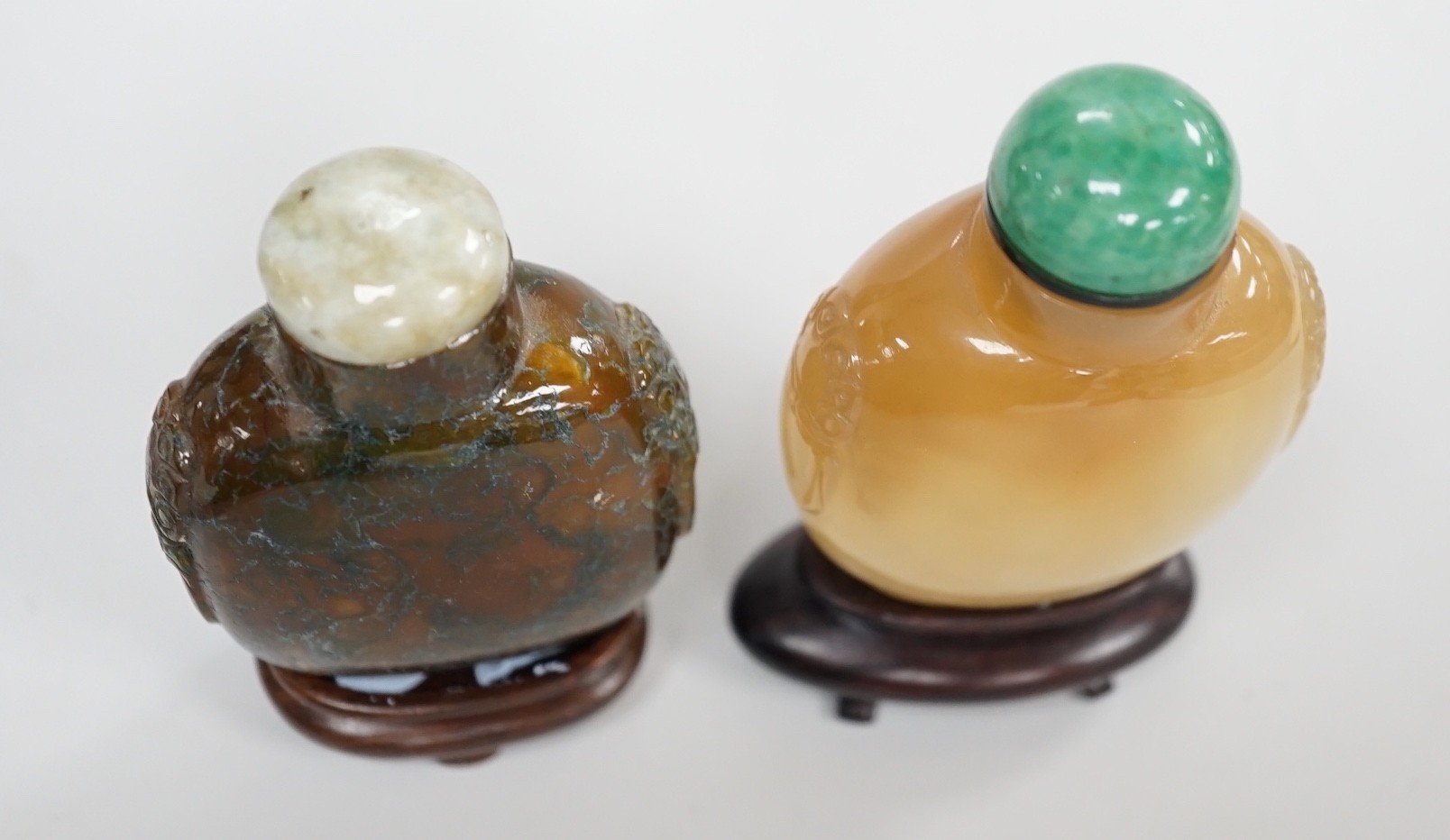 A Chinese honey coloured agate mask and ring handled snuff bottle and a dendritic chalcedony (moss agate) mask and ring handled snuff bottle, 5.7cm, both 1780-1880